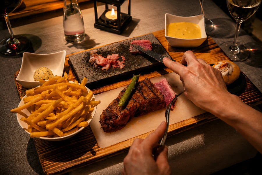 Gast schneidet Fleisch auf dem heißen Stein im Restaurant Hazienda in Niederhünigen.