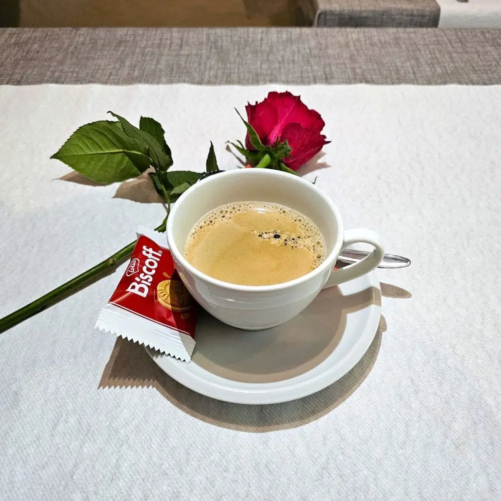 Kaffee neben einer Rose auf einem Tisch